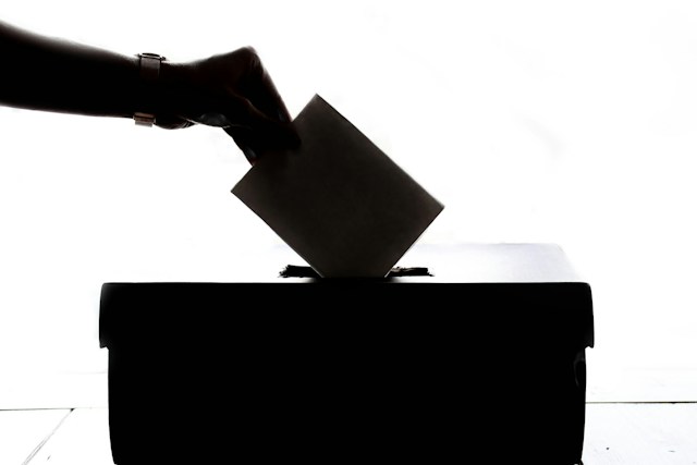 A person is casting a vote into a box